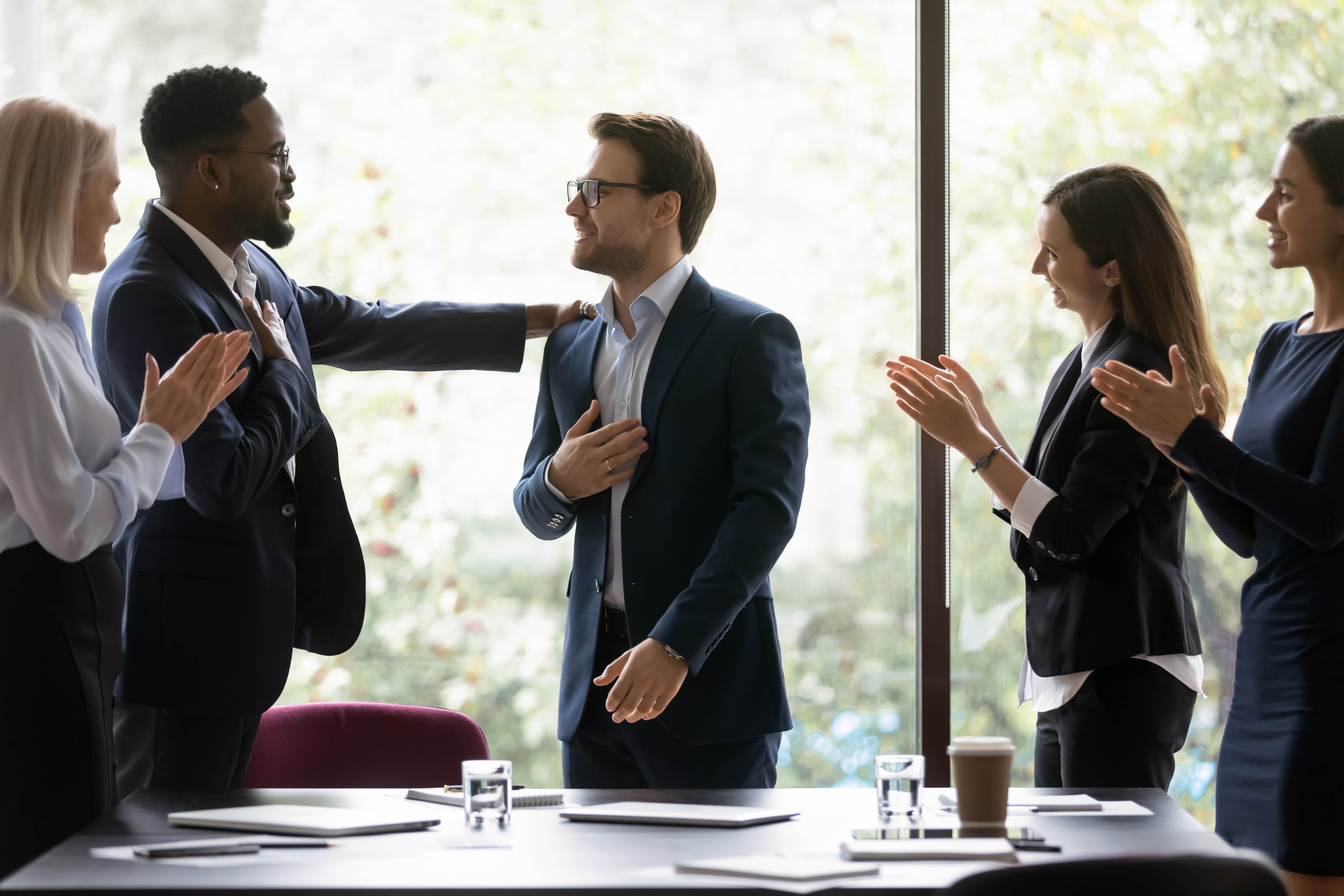 Group of young professionals standing in a board room clapping